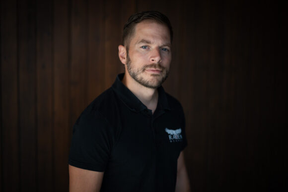 Porträt von Mirco Brühwiler, der vor einem dunkeln Hintergrund steht.