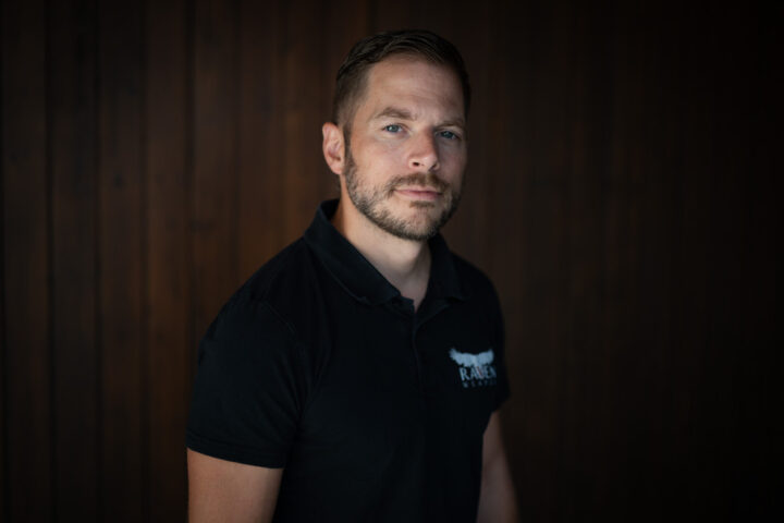 Porträt von Mirco Brühwiler, der vor einem dunkeln Hintergrund steht.