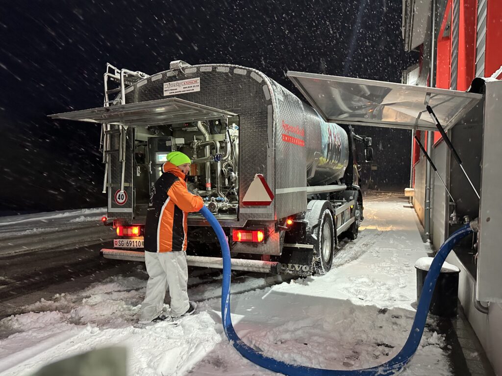 Der Milchlieferant bringt die frische Milch. Er steht im Schnee.