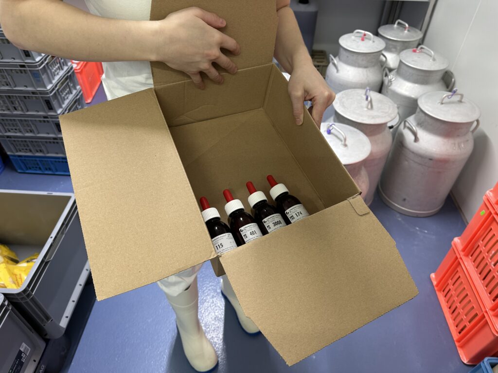 Eine Kartonbox mit Fläschchen die Kulturen für den Käse enthalten.