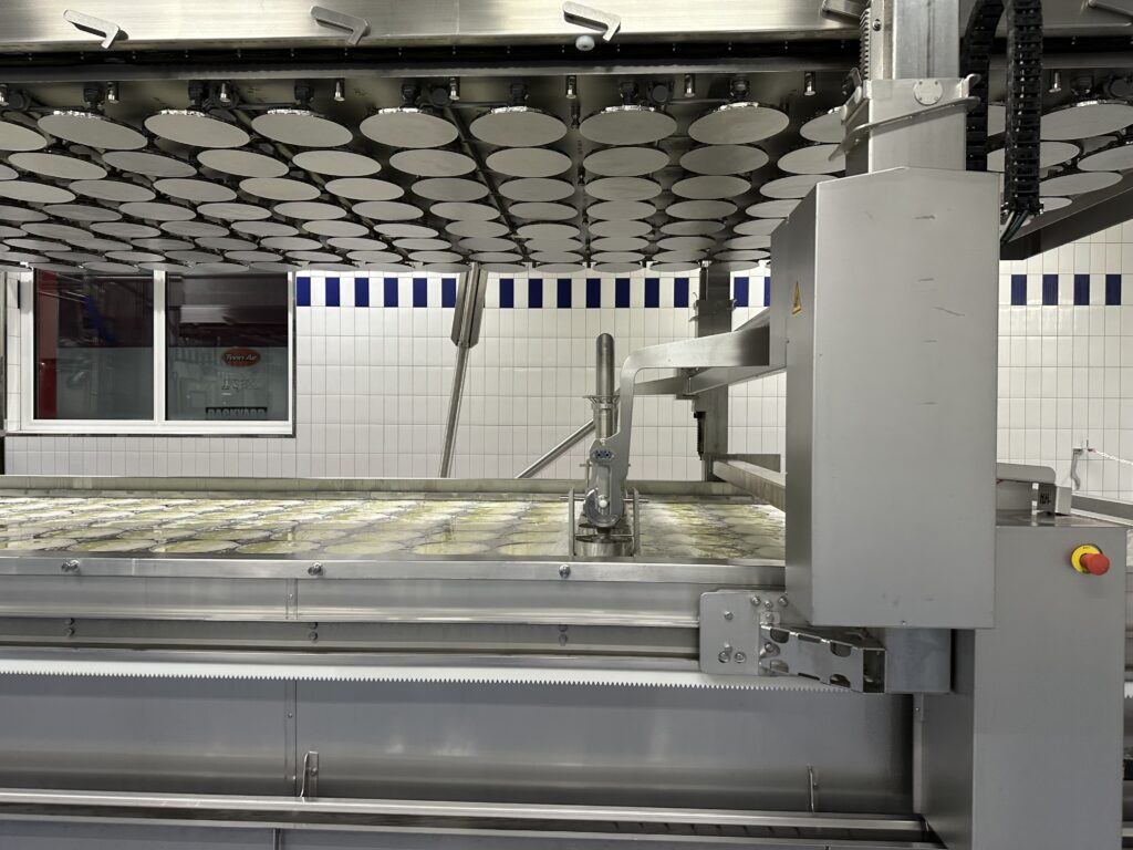 Eine Maschine füllt den Käse-Bruch ab.