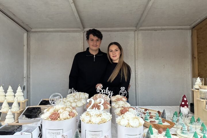 Endrit und Valentina Musliji stehen an ihrem Marktstand. vor ihnen stehen ihre Kerzen.