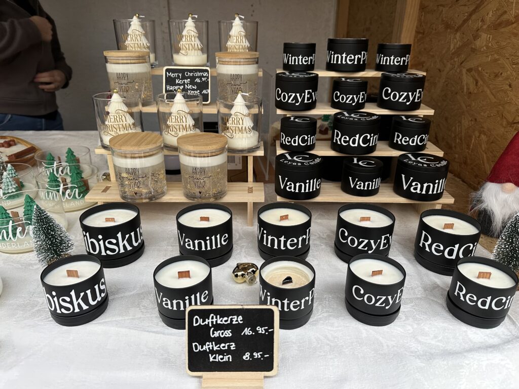 Kerzen in schwarzen Behältern mit weisser Aufschrift.