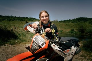 Vanessa König: Eine junge Frau steht hinter ihrem orangenen Motorrad und lächelt in die Kamera.
